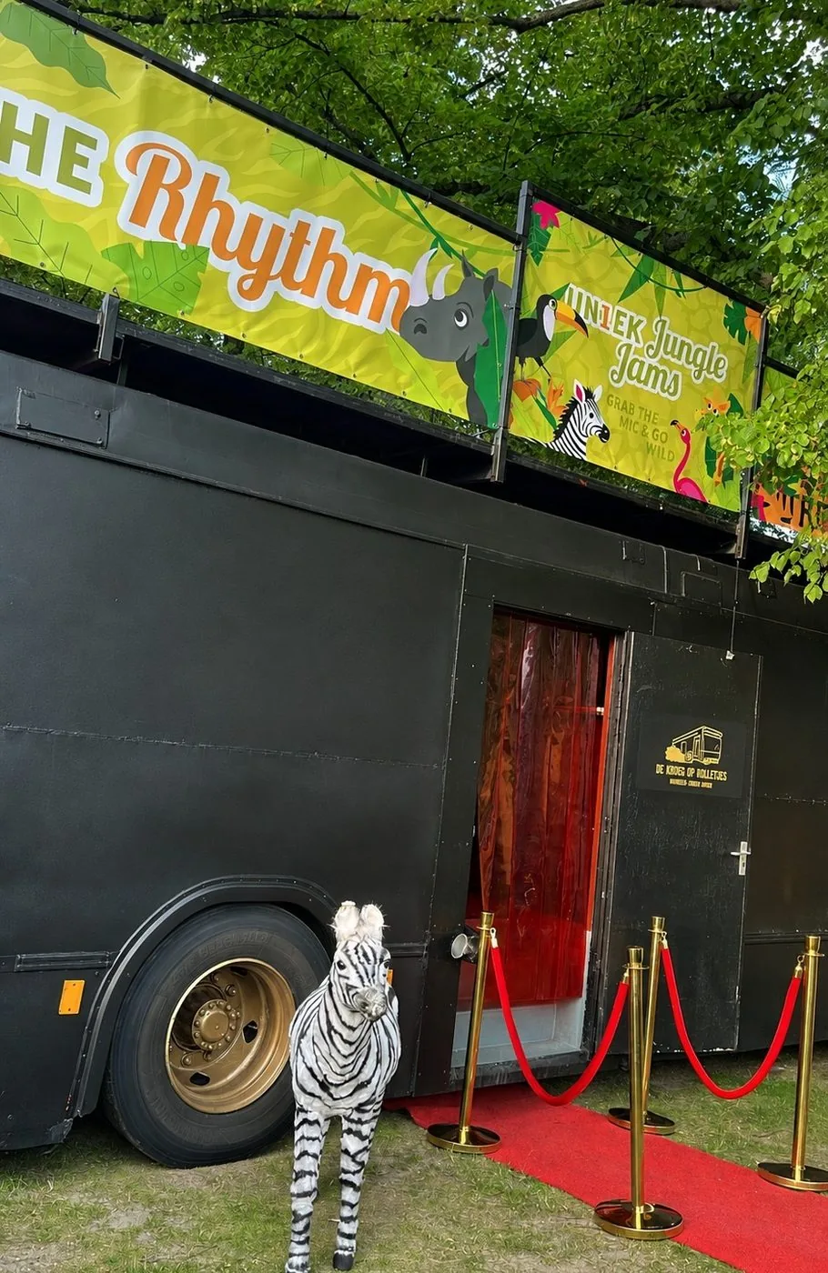 De Kroegbus op een bedrijfsfestival met een spandoek op het dak en de rode loper bij de ingang.