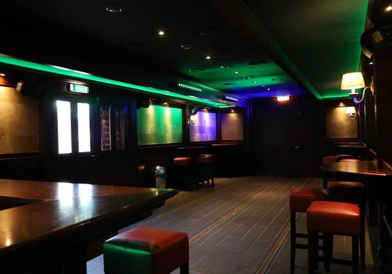 Het interieur van Kroeg XL met houten lambrisering, statafels en sfeerverlichting.
